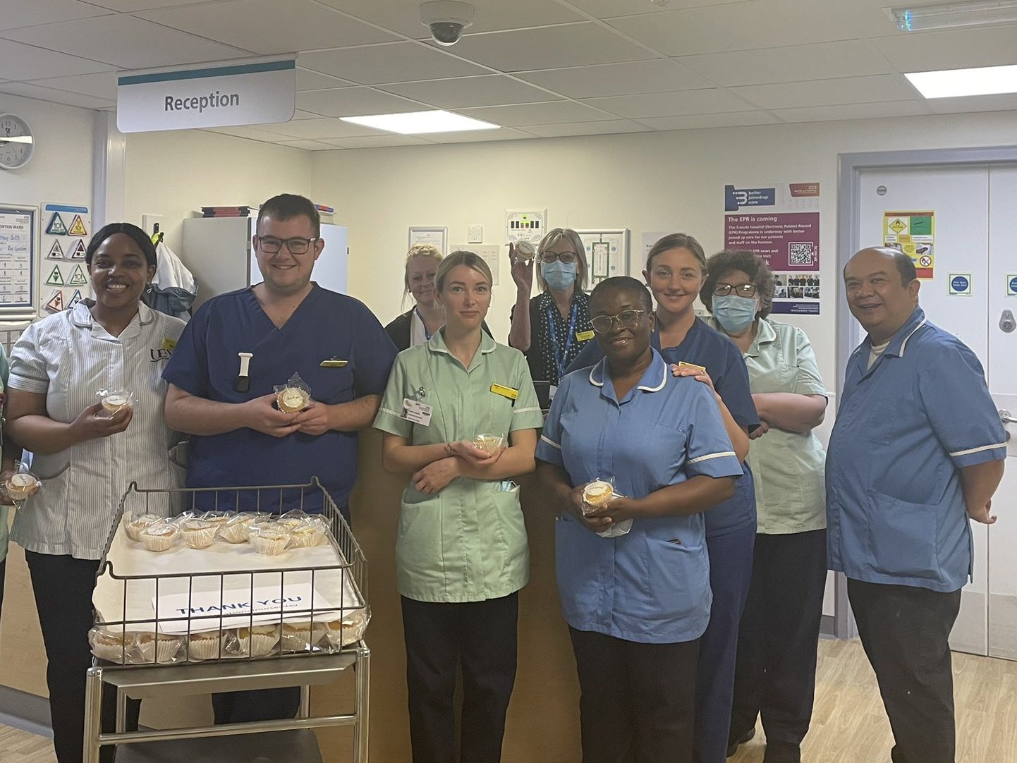 Tom Edwards in blue scrubs celebrating International Nurses Day with ward staff on West Newton Ward.