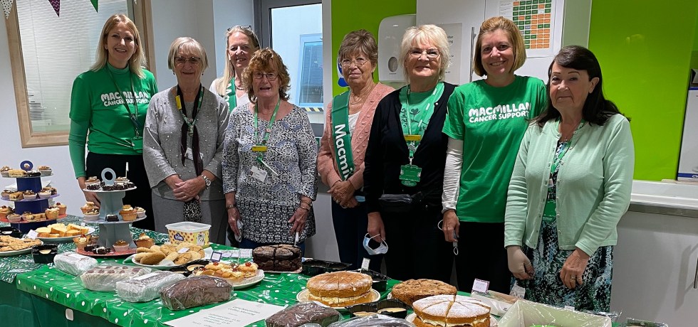 Macmillan supporters behind a desk filled with cakes