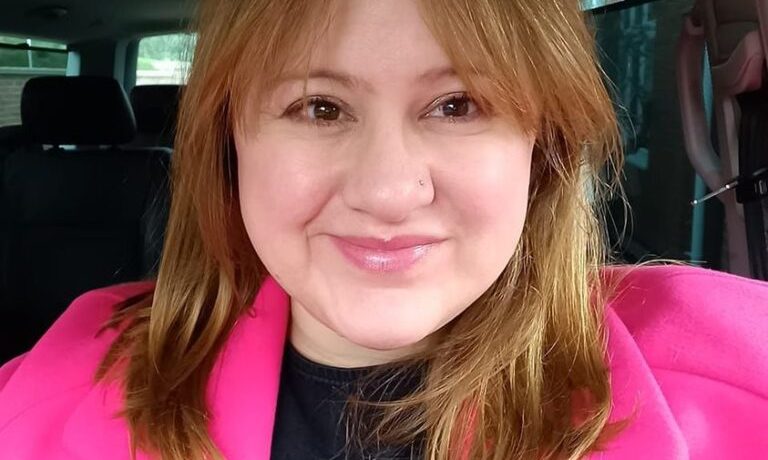 A picture of Kate Clark wearing a pink coat