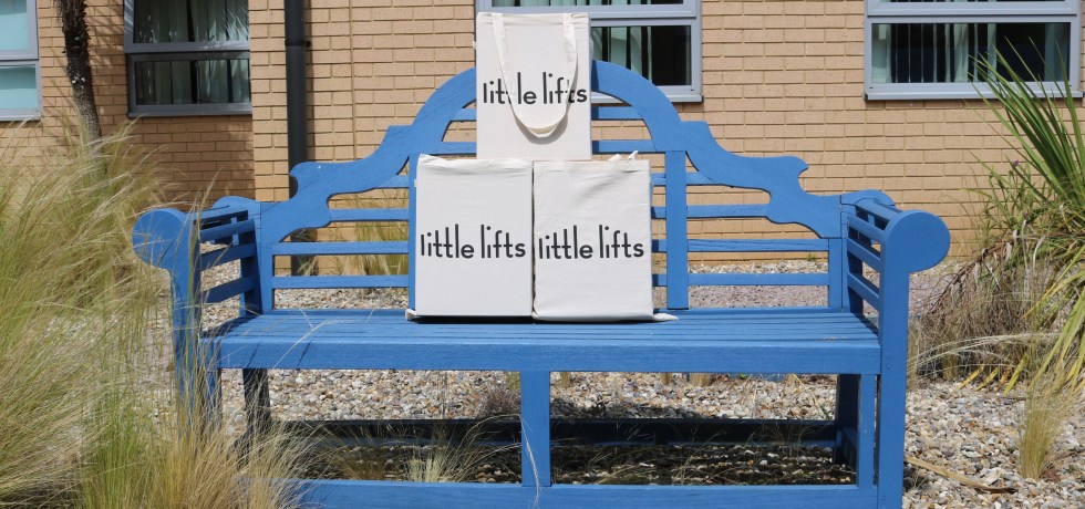 A picture of the Little Lift boxes sat on a blue bench.