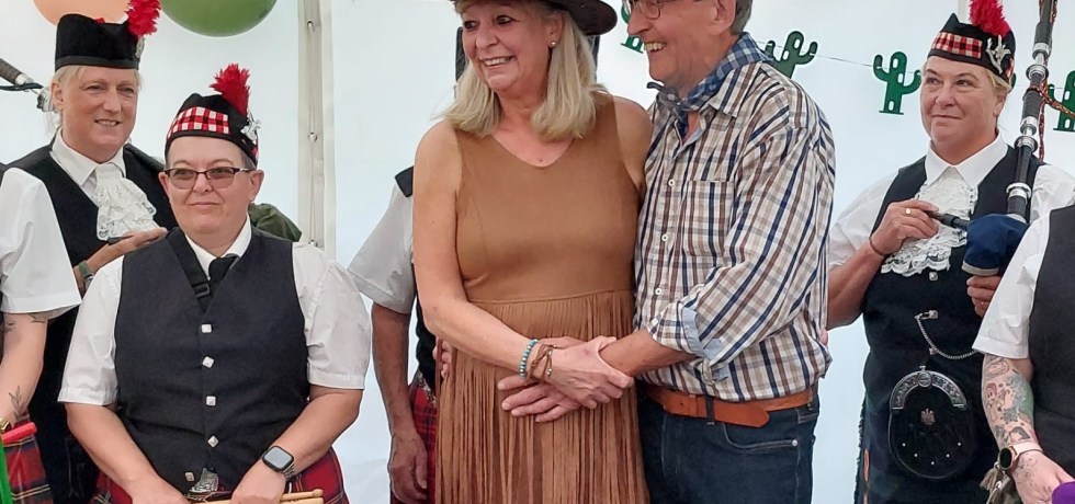 A picture of John and Geraldine Rupp dancing around a Scottish band wearing cowboy attire