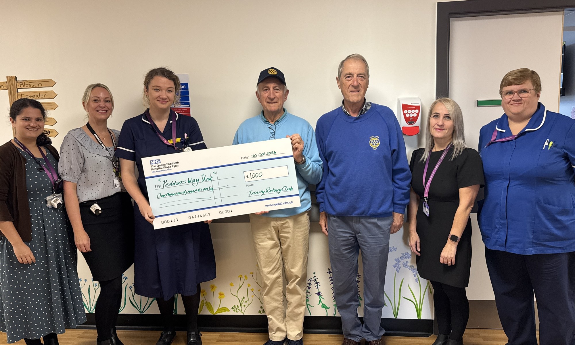 A picture of the Trinity Rotary Club handing a giant novelty cheque worth £1,000 to the palliative for their end of life unit