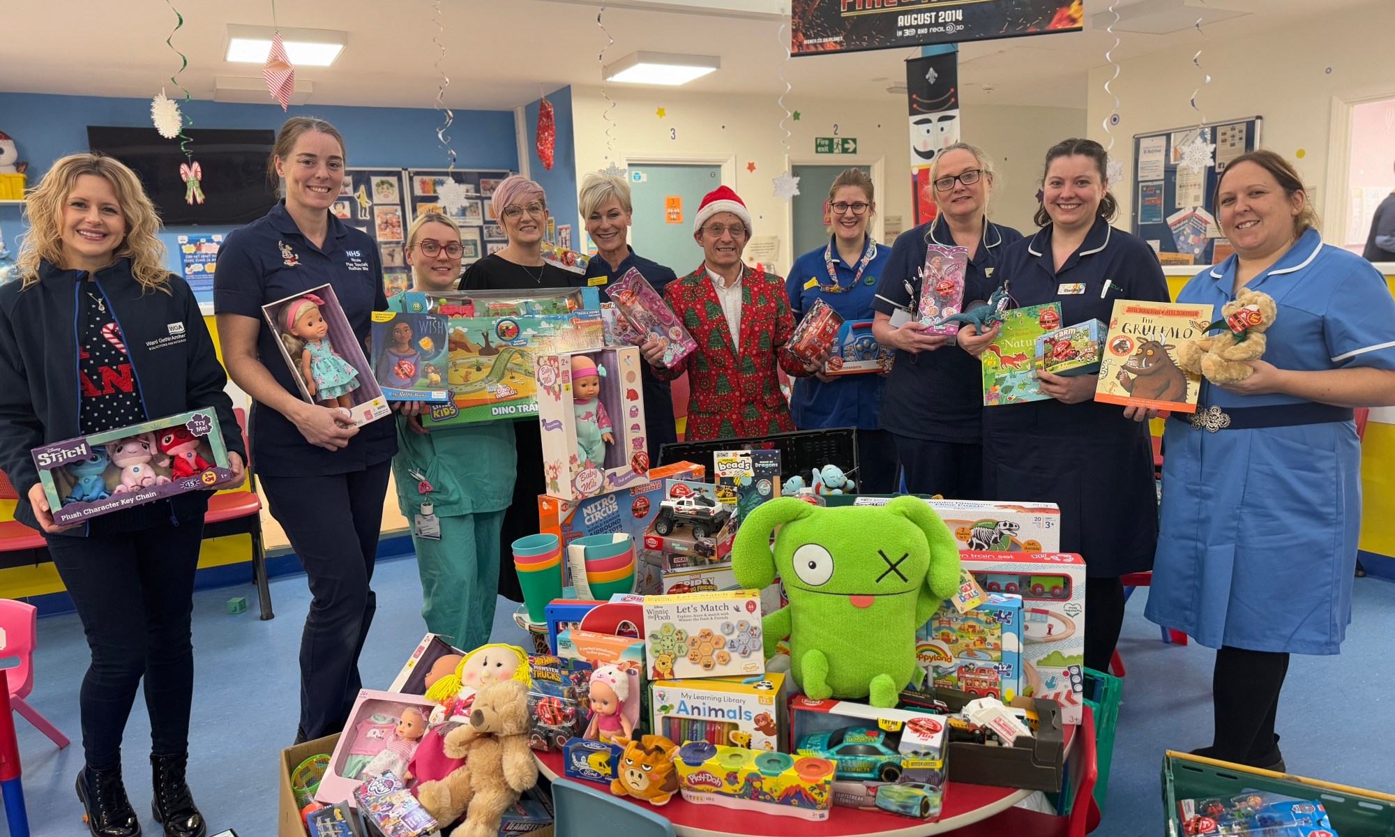 People standing around the donated toys posing for a photo.