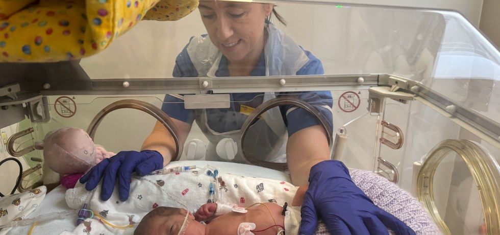 Nurse caring for a new-born baby in a incubator.