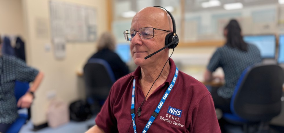 Volunteer sitting behind a desk wearing a headset.