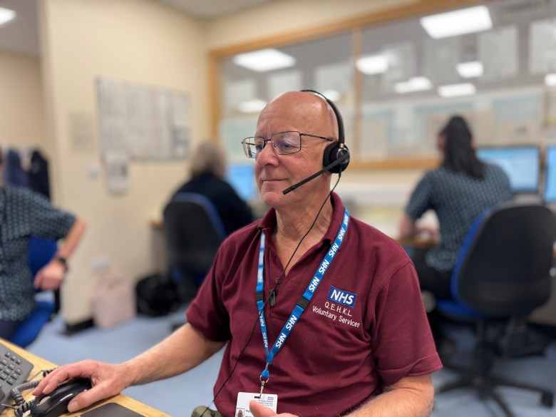 Volunteer sitting behind a desk wearing a headset.