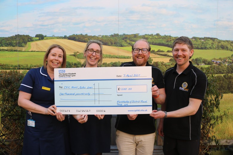 Two members of the Hunstanton and District Round table (Robert Brown and Glenn Perkins) passing a giant novelty cheque to two nurses worth £1,000.
