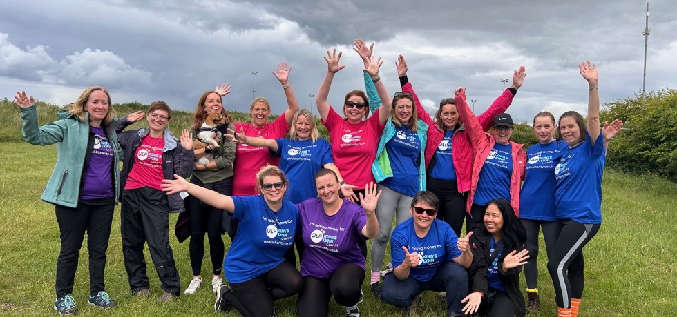 A photo of the QEHKL Walkers wearing "I'm raising money for the QEHKL Charity" t-shirts, smiling and waving their hands in the air