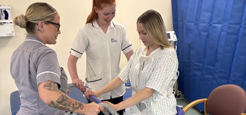 A photo of two physio therapists (Tabitha & Sam) assisting a patient