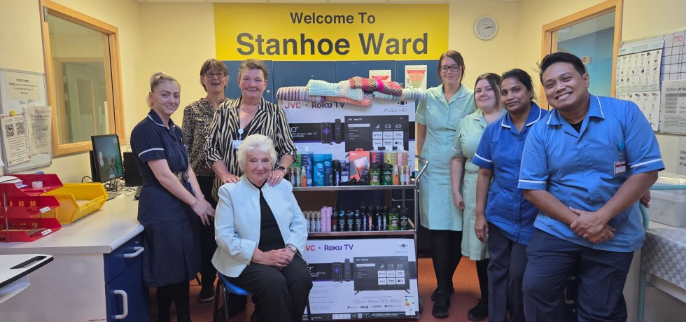 A photo of staff nurses with two flat screen television sets and lots of body wash, deodorants, etc. The mother and daughter duo can be found on the far right with Val sat in a chair.