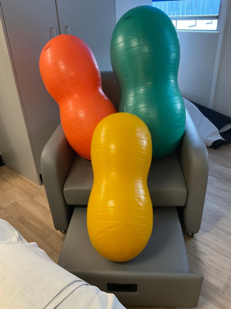 A photo of green, orange and yellow peanut-shaped plastic birthing balls