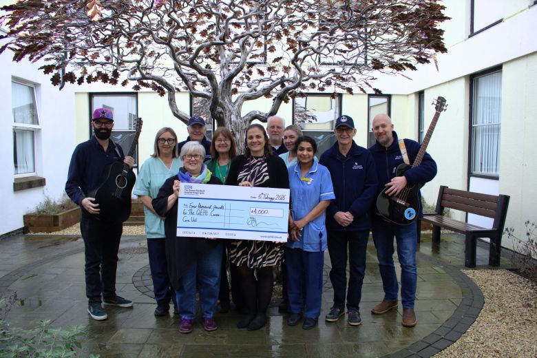 Nelson’s Shanty Men holding guitars and a giant novelty cheque with nursing staff around