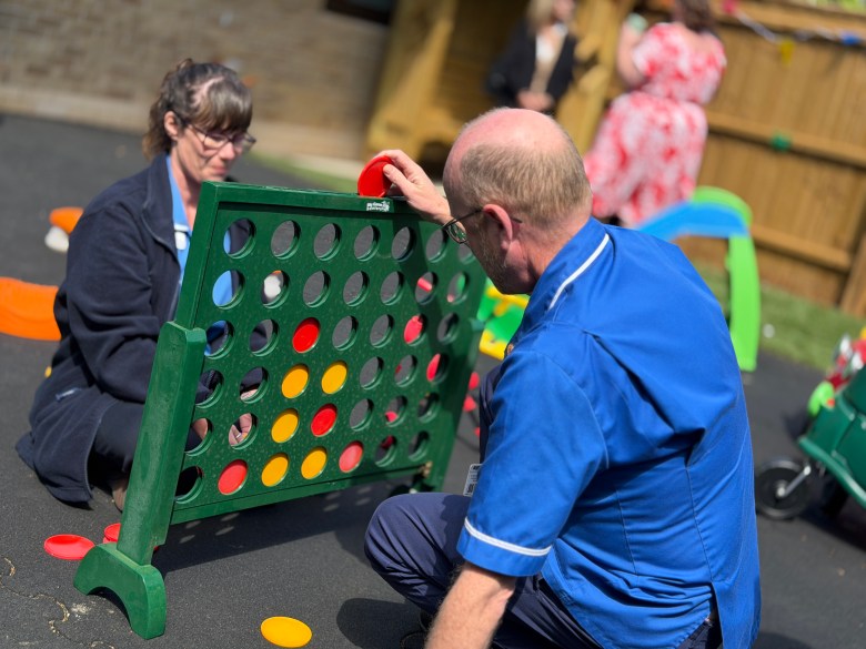 A photo of two nurses playing giant novelty connect four in the newly refurbished garden.