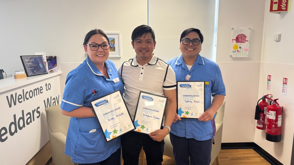 A photo of Kirsty Phillips, Geminick Siriban and Jeffrey Rojas receiving the Living Our Values Award 