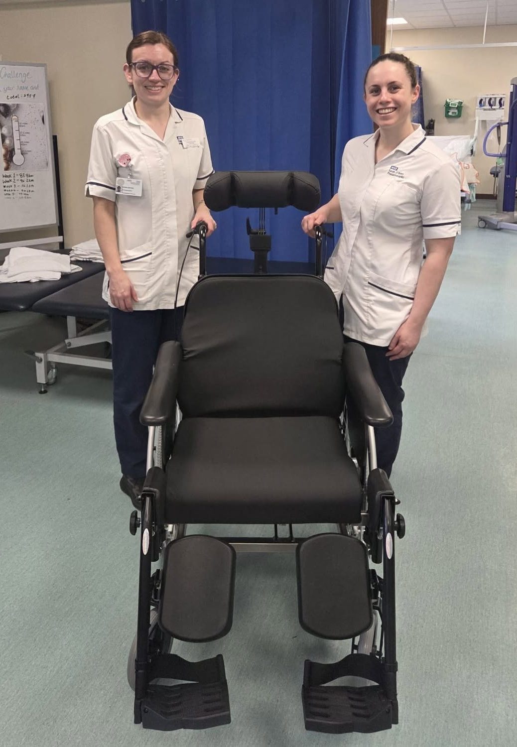 A photo of two nurses stood next to the specialist wheelchair