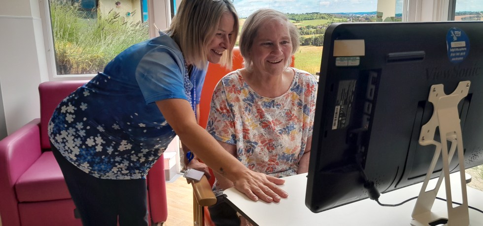 A photo of a dementia specialist nurse introducing a smiling patient to the computer system, RITA