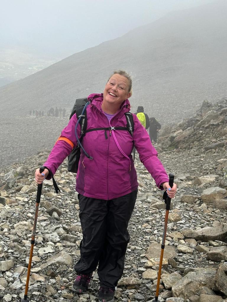 Janet Mick with walking sticks on the mountin