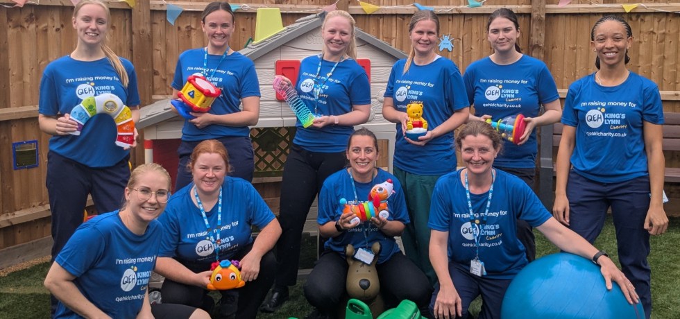 A photo of the play team wearing "I'm raising money for QEHKL Charity" holding various toys in an outdoor play area.