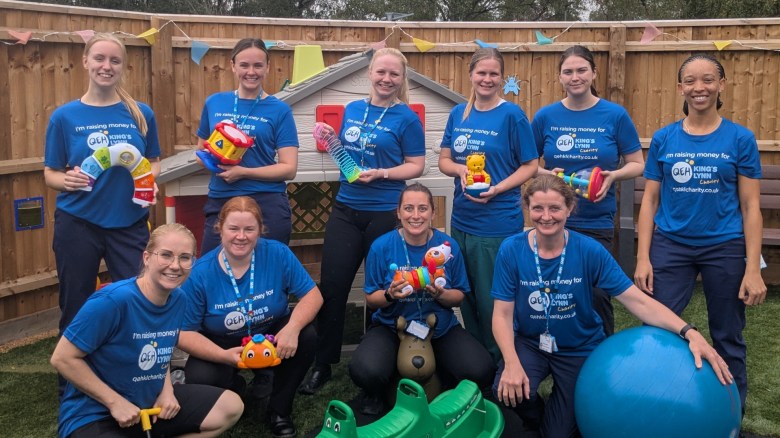 A photo of the play team wearing "I'm raising money for QEHKL Charity" holding various toys in an outdoor play area.